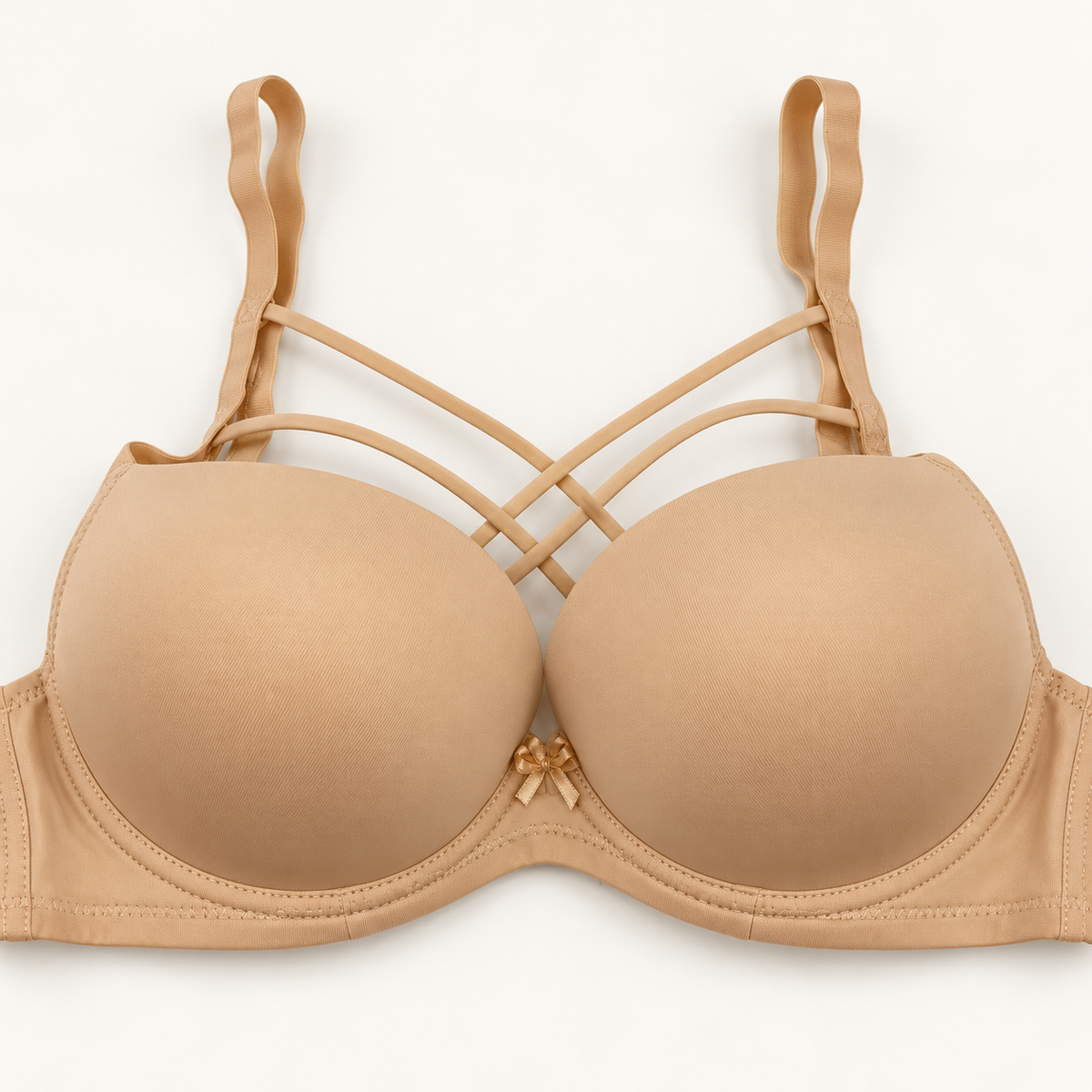 Nude beige push-up bra with smooth cups and narrow decorative straps crossing above the cups. A plain band and small centre bow complete the design.