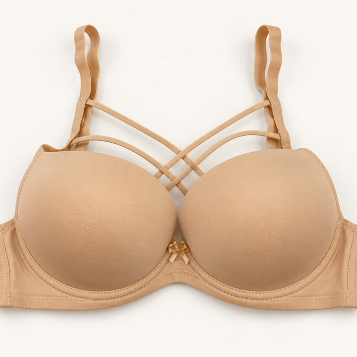 Nude beige push-up bra with smooth cups and narrow decorative straps crossing above the cups. A plain band and small centre bow complete the design.